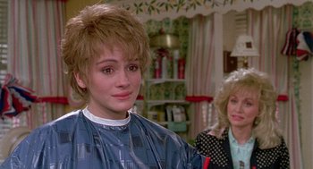 Movie still from “Steel Magnolias” (1989), directed by Herbert Ross – A woman with a haircut in front of another woman in a room; Close Up shot, Over the shoulder angle