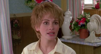 Movie still from “Steel Magnolias” (1989), directed by Herbert Ross – A young woman with short brown hair wearing a white shirt; Close Up shot, Over the shoulder angle
