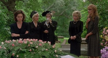 Movie still from “Steel Magnolias” (1989), directed by Herbert Ross – A group of women standing next to each other at a funeral; Wide shot, Low angle