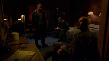 Movie still from “Breaking Bad” (2008), created by Vince Gilligan – A group of men sitting in a living room next to each other; Wide shot, Low angle
