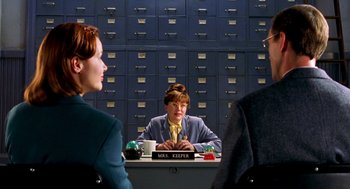 Movie still from “Stuart Little” (1999), directed by Rob Minkoff – Three people are sitting at a desk in front of a card catalog; Medium shot, Over the shoulder angle