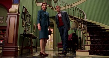 Movie still from “Stuart Little” (1999), directed by Rob Minkoff – A man and a woman standing next to each other in front of a staircase; Wide shot, Low angle