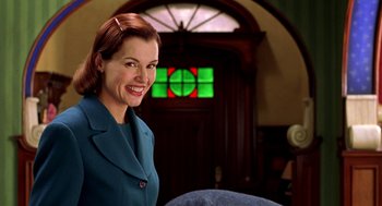 Movie still from “Stuart Little” (1999), directed by Rob Minkoff – A woman in a blue suit smiling for the camera; Medium shot, Over the shoulder angle