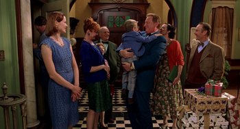 Movie still from “Stuart Little” (1999), directed by Rob Minkoff – A group of people standing in a room with a man holding a baby; Medium shot, Over the shoulder angle