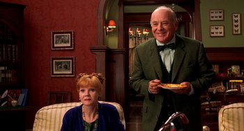 Movie still from “Stuart Little” (1999), directed by Rob Minkoff – An older man standing next to an older woman in a room; Medium shot, Over the shoulder angle
