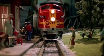 Movie still from “Stuart Little” (1999), directed by Rob Minkoff – A red and yellow train on a train track; Wide shot, High angle