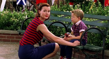 Movie still from “Stuart Little” (1999), directed by Rob Minkoff – A woman sitting on a park bench with a young boy; Medium shot, Low angle