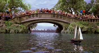 Movie still from “Stuart Little” (1999), directed by Rob Minkoff – A group of people sitting on top of a bridge over a river; Extreme Wide shot, High angle