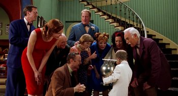 Movie still from “Stuart Little” (1999), directed by Rob Minkoff – A group of people gathered around a large silver pot; Medium shot, High angle