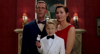 Movie still from “Stuart Little” (1999), directed by Rob Minkoff – A man , woman , and a boy are posing for a picture; Medium shot, Over the shoulder angle