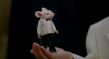 Movie still from “Stuart Little” (1999), directed by Rob Minkoff – A person holding a toy mouse wearing a suit and bow tie; Extreme Close Up shot, High angle
