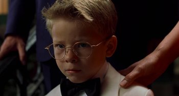 Movie still from “Stuart Little” (1999), directed by Rob Minkoff – A young boy wearing glasses and a bow tie; Close Up shot, Over the shoulder angle