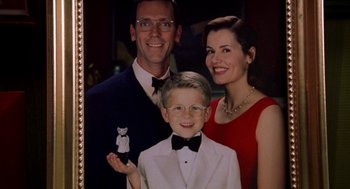 Movie still from “Stuart Little” (1999), directed by Rob Minkoff – A man , woman , and a boy are posing for a picture; Close Up shot, High angle