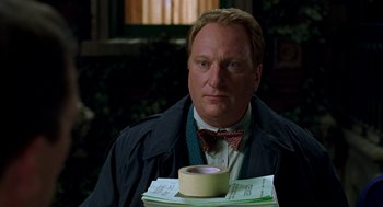 Movie still from “Stuart Little” (1999), directed by Rob Minkoff – A man holding a roll of duct tape in front of him; Close Up shot, Low angle