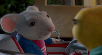 Movie still from “Stuart Little 2” (2002), directed by Rob Minkoff – A white mouse sitting in a car with a pink jacket on; Close Up shot, Over the shoulder angle