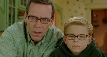 Movie still from “Stuart Little 2” (2002), directed by Rob Minkoff – A man and a boy wearing glasses posing for a picture; Close Up shot, Over the shoulder angle