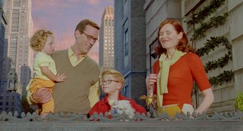 Movie still from “Stuart Little 2” (2002), directed by Rob Minkoff – A man , woman , and a child standing in front of a building; Medium shot, Over the shoulder angle