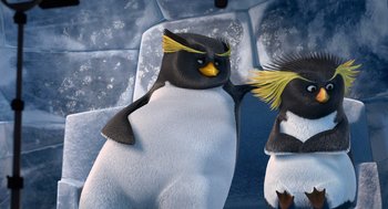 Movie still from “Surf's Up” (2007), directed by Chris Buck – Two penguins are sitting on a couch and one penguin has yellow feathers on its head and the other penguin has yellow feathers on its head; Close Up shot, High angle