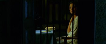 A woman sitting in a jail cell looking out the window