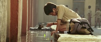 A young boy is playing with a bird in the water