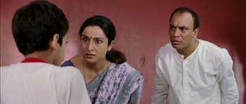 A woman and a man standing next to each other in front of a pink wall