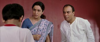 A woman and a man standing next to each other in front of a pink wall