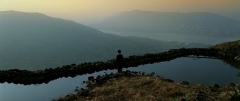 A man standing on top of a hill near a body of water
