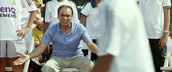 Movie still from “Like Stars on Earth” (2007), directed by Aamir Khan – A man sitting on a chair in front of a group of people; Medium shot, Low angle