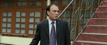 Movie still from “Like Stars on Earth” (2007), directed by Aamir Khan – A man in a suit and tie standing in front of a building; Medium shot, Low angle