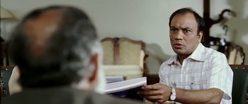 Movie still from “Like Stars on Earth” (2007), directed by Aamir Khan – A man sitting in front of another man holding a book; Medium shot, Over the shoulder angle