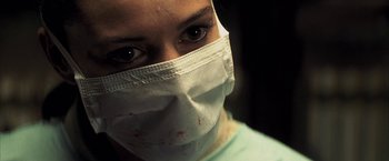 Movie still from “Tears of the Sun” (2003), directed by Antoine Fuqua – A woman wearing a surgical mask with blood on her face; Close Up shot, Low angle