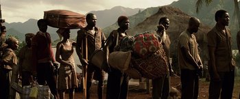 Movie still from “Tears of the Sun” (2003), directed by Antoine Fuqua – A group of people standing around a mountain; Wide shot, Low angle