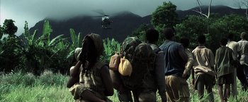 Movie still from “Tears of the Sun” (2003), directed by Antoine Fuqua – A group of people are gathered in a field looking at a helicopter; Extreme Wide shot, High angle