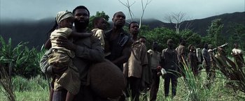 Movie still from “Tears of the Sun” (2003), directed by Antoine Fuqua – A group of people standing in a field; Medium shot, Low angle