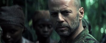 Movie still from “Tears of the Sun” (2003), directed by Antoine Fuqua – A man with a beard and a scar on his forehead; Close Up shot, Over the shoulder angle