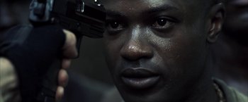 Movie still from “Tears of the Sun” (2003), directed by Antoine Fuqua – A person holding a gun up to their face; Close Up shot, Low angle