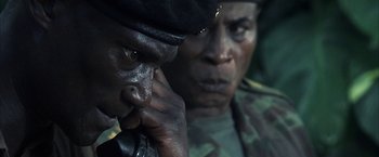Movie still from “Tears of the Sun” (2003), directed by Antoine Fuqua – Two men in fatigues are looking into the distance; Close Up shot, Over the shoulder angle