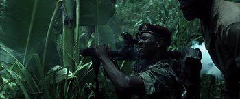 Movie still from “Tears of the Sun” (2003), directed by Antoine Fuqua – A man with a rifle in the woods looking through a telescope; Medium shot, Low angle