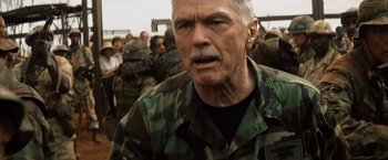 An older man in a military uniform is looking at the camera