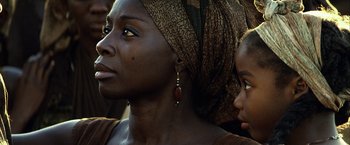 Movie still from “Tears of the Sun” (2003), directed by Antoine Fuqua – A woman wearing a headscarf and earrings looking to her left; Close Up shot, Over the shoulder angle