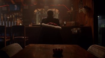 Movie still from “Breaking Bad” (2008), created by Vince Gilligan – A man sitting at a bar in a dark room; Wide shot, Low angle