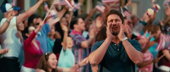 Movie still from “The Bounty Hunter” (2010), directed by Andy Tennant – A crowd of people standing in front of american flags; Medium shot, Low angle