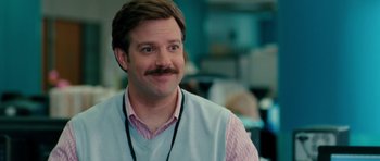 Movie still from “The Bounty Hunter” (2010), directed by Andy Tennant – A man with a beard and mustache wearing a vest; Close Up shot, Over the shoulder angle