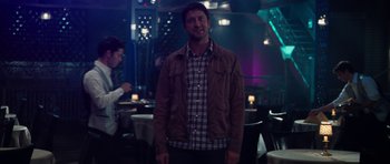 Movie still from “The Bounty Hunter” (2010), directed by Andy Tennant – A man standing in front of a table in a restaurant; Medium shot, Over the shoulder angle