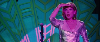 Movie still from “The Bounty Hunter” (2010), directed by Andy Tennant – A woman standing in front of a microphone on a stage; Medium shot, Low angle