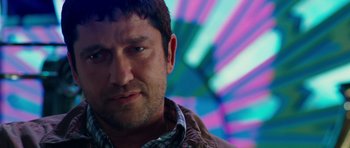 Movie still from “The Bounty Hunter” (2010), directed by Andy Tennant – A man's face in front of a colorful background; Close Up shot, Over the shoulder angle