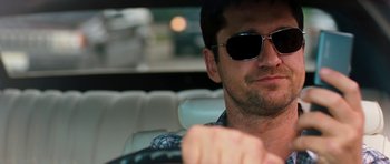 Movie still from “The Bounty Hunter” (2010), directed by Andy Tennant – A person wearing sunglasses driving a car; Close Up shot, Over the shoulder angle