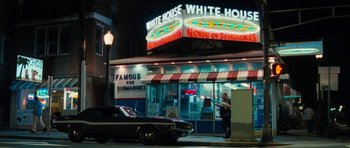 Movie still from “The Bounty Hunter” (2010), directed by Andy Tennant – A man standing in front of a restaurant at night; Wide shot, Low angle