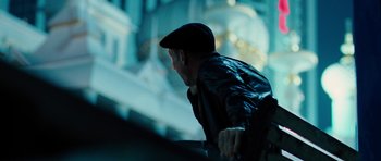 Movie still from “The Bounty Hunter” (2010), directed by Andy Tennant – A man wearing a hat and a leather jacket looking over a railing; Medium shot, Low angle
