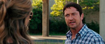 Movie still from “The Bounty Hunter” (2010), directed by Andy Tennant – A man in plaid shirt talking to another man in a park; Close Up shot, Over the shoulder angle